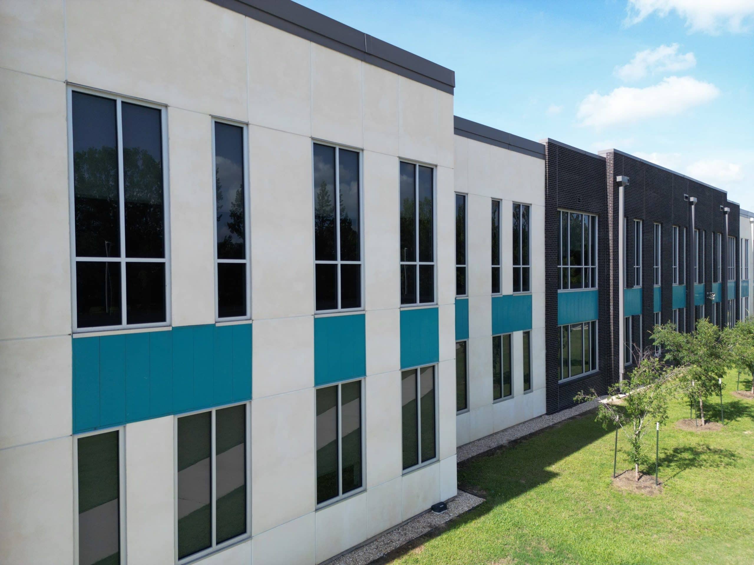 The exterior of an office building with blue windows and roofing.